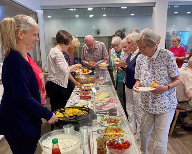 Menschen stehen nach einer Veranstaltung gemeinsam an einem Buffet