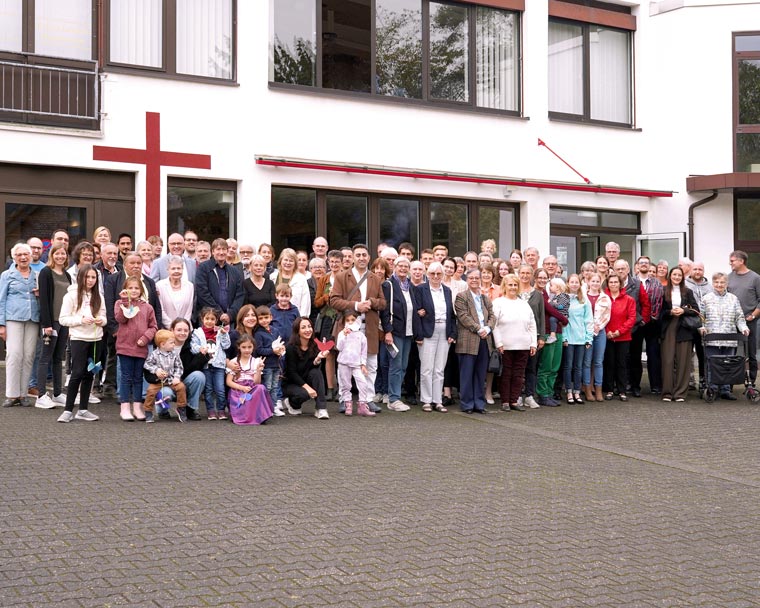 Menschen der Brüdergemeinde stehen gemeinsam vor dem Gemeindehaus